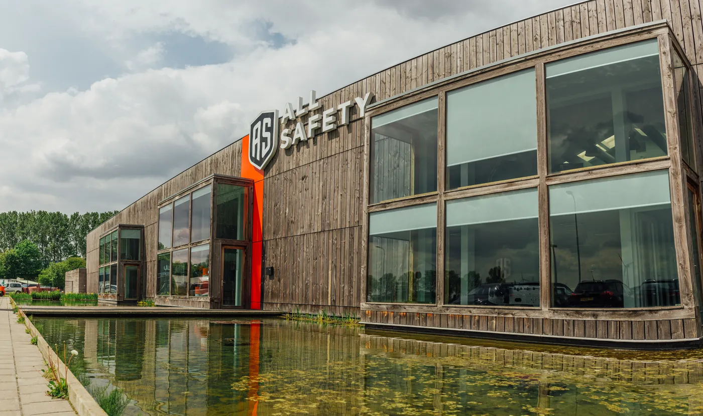 Het houten bedrijfspand van All Safety in Terneuzen, weerspiegeld in het water.