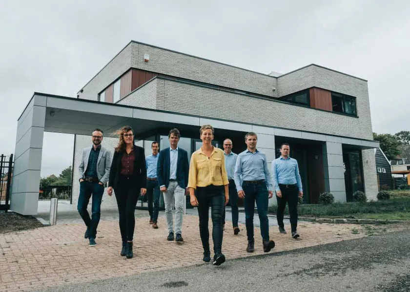 Het team van KG Adviseurs loopt samen voor hun kantoor.