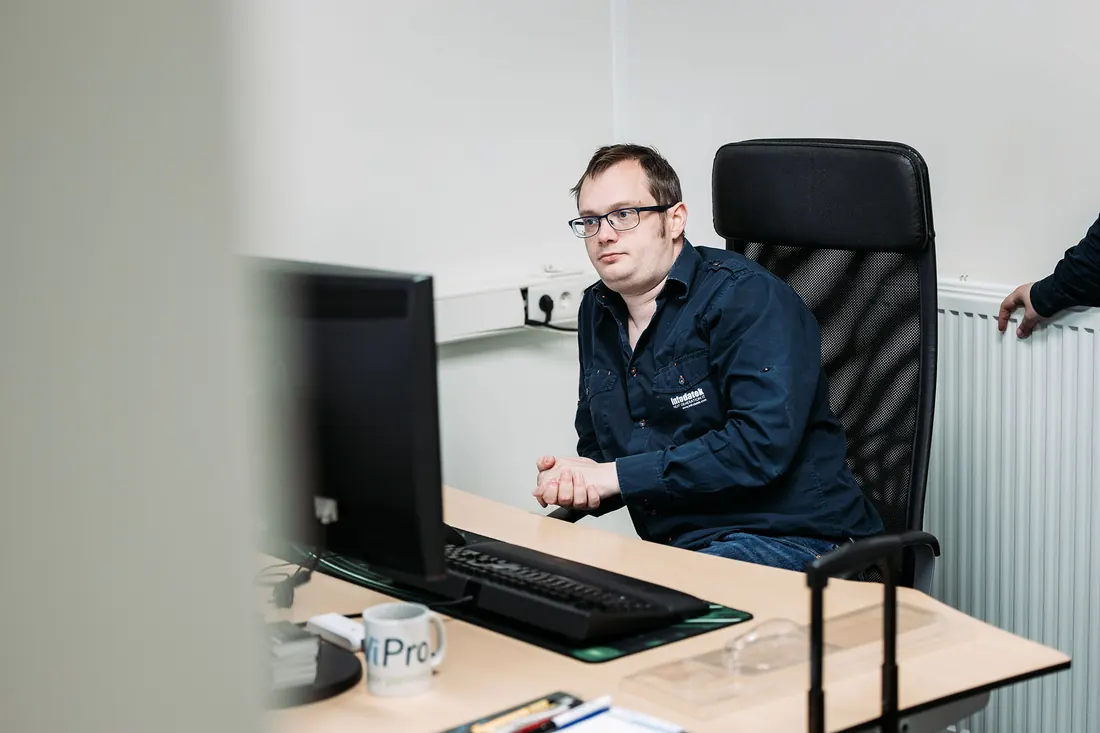 Een engineer van Infodatek Group met bril aan zijn bureau, achter zijn scherm.