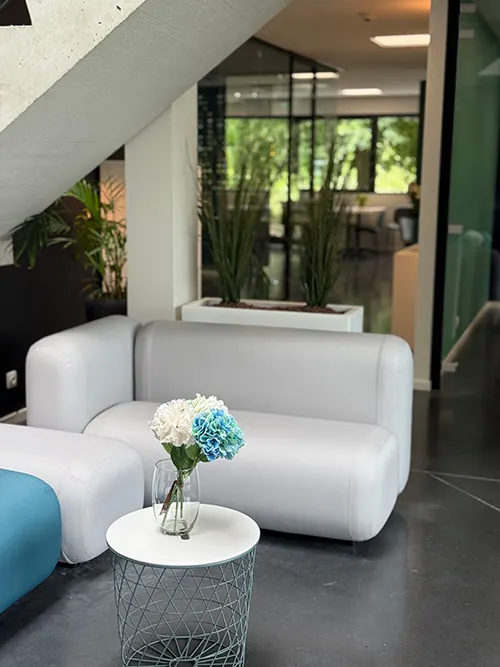Een witte bank en een bijzettafel met bloemen in het kantoor van Infodatek Group.