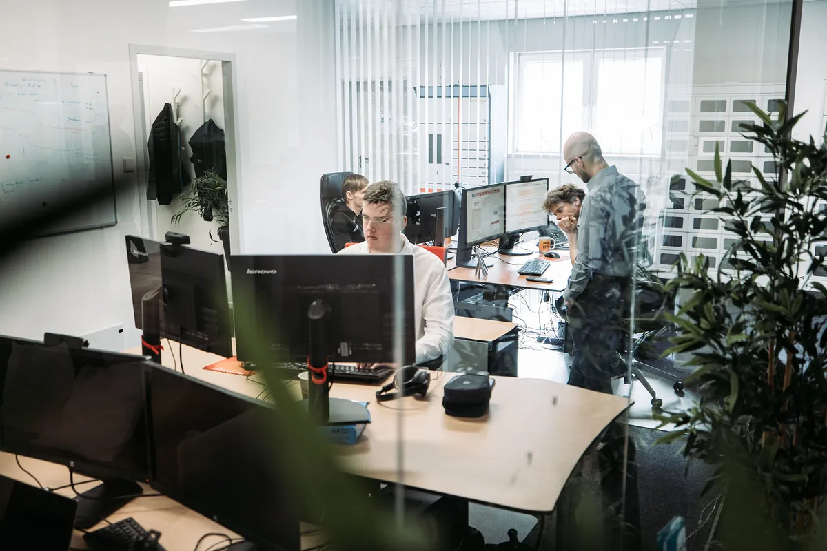 Collega's van Infodatek Group aan hun werkplekken in een licht kantoor.