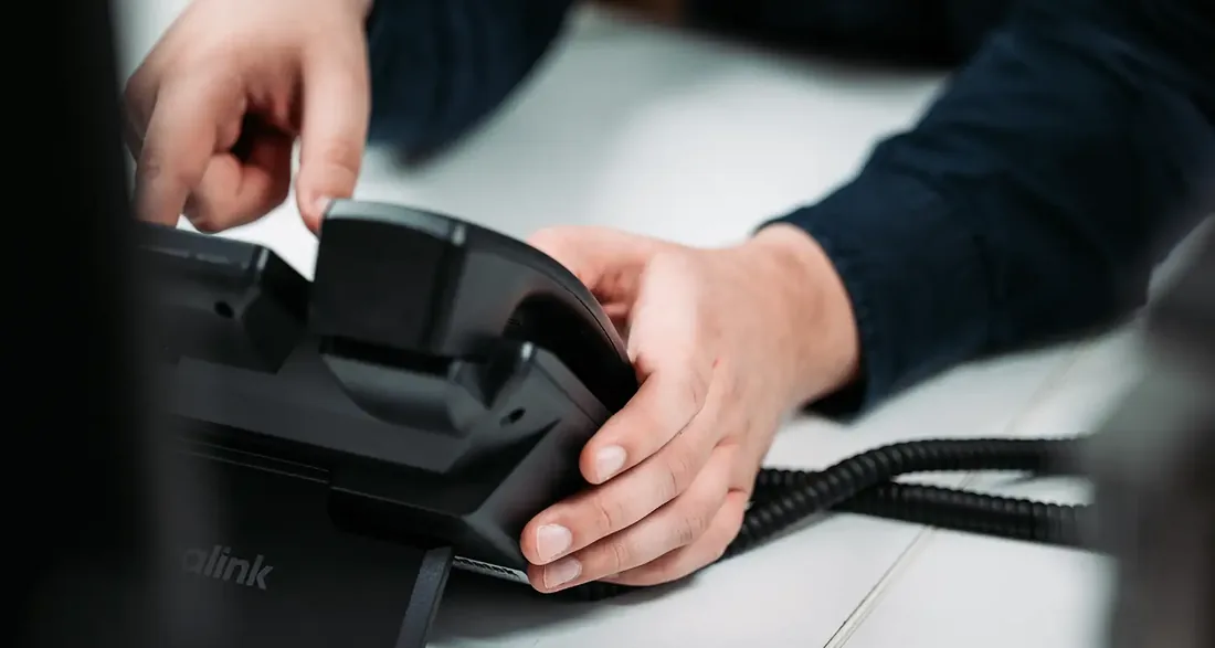 Een collega van Infodatek Group neemt de hoorn van de bureautelefoon op.